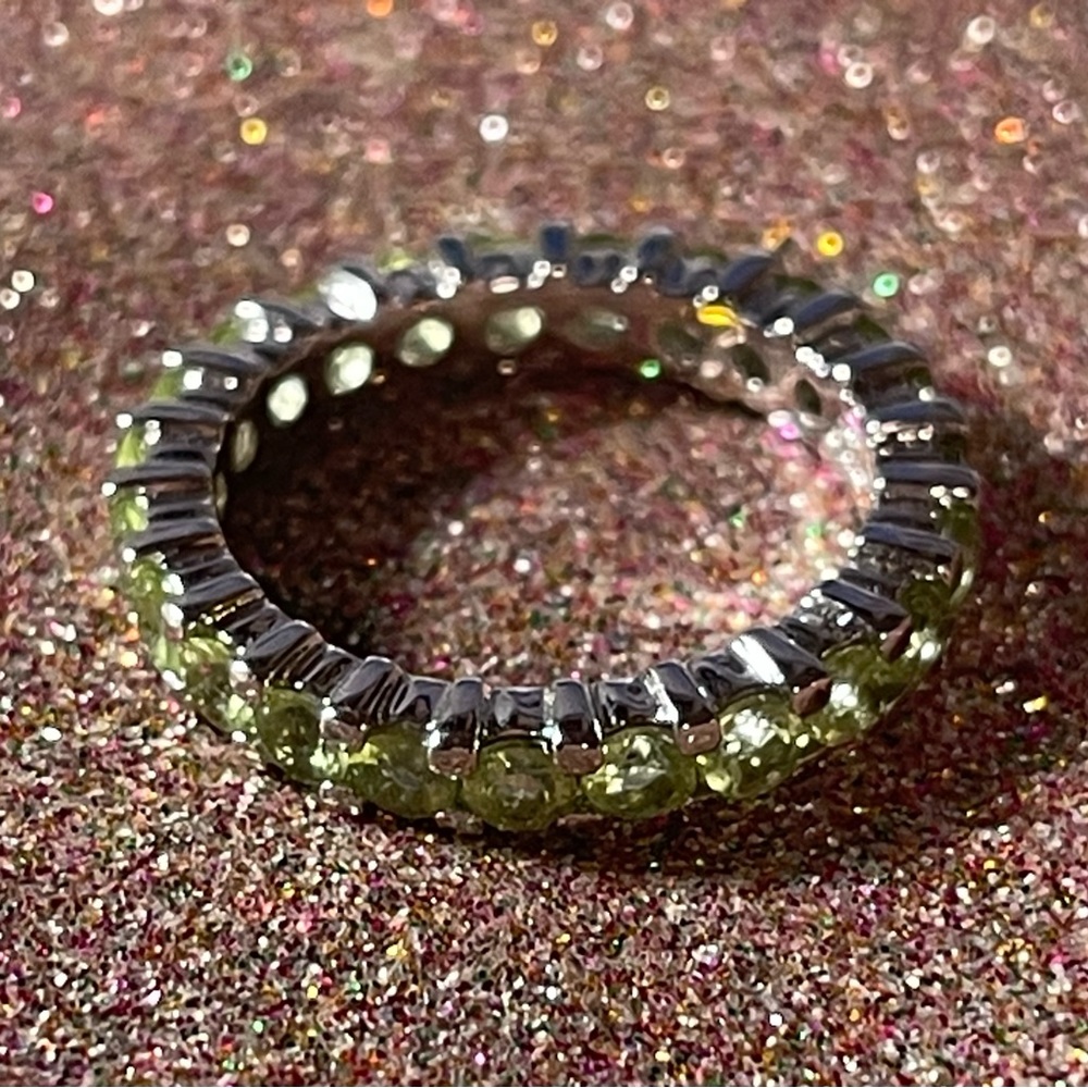 Sterling silver ring with green stones all around.